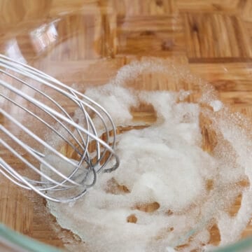 Gelatin being mixed with cold water in a bowl until thickened into a gel-like consistency.
