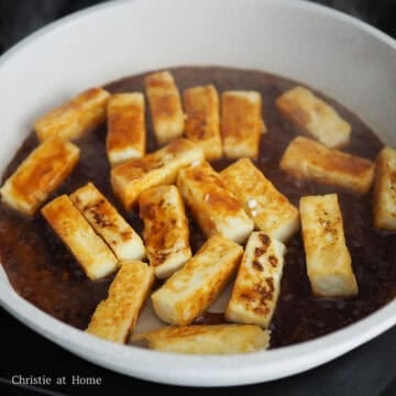Reduce to low heat and pour in sauce. Let it thicken and then gently toss with tofu. Once each tofu piece is coated in the thickened sauce, remove and transfer to a serving plate.