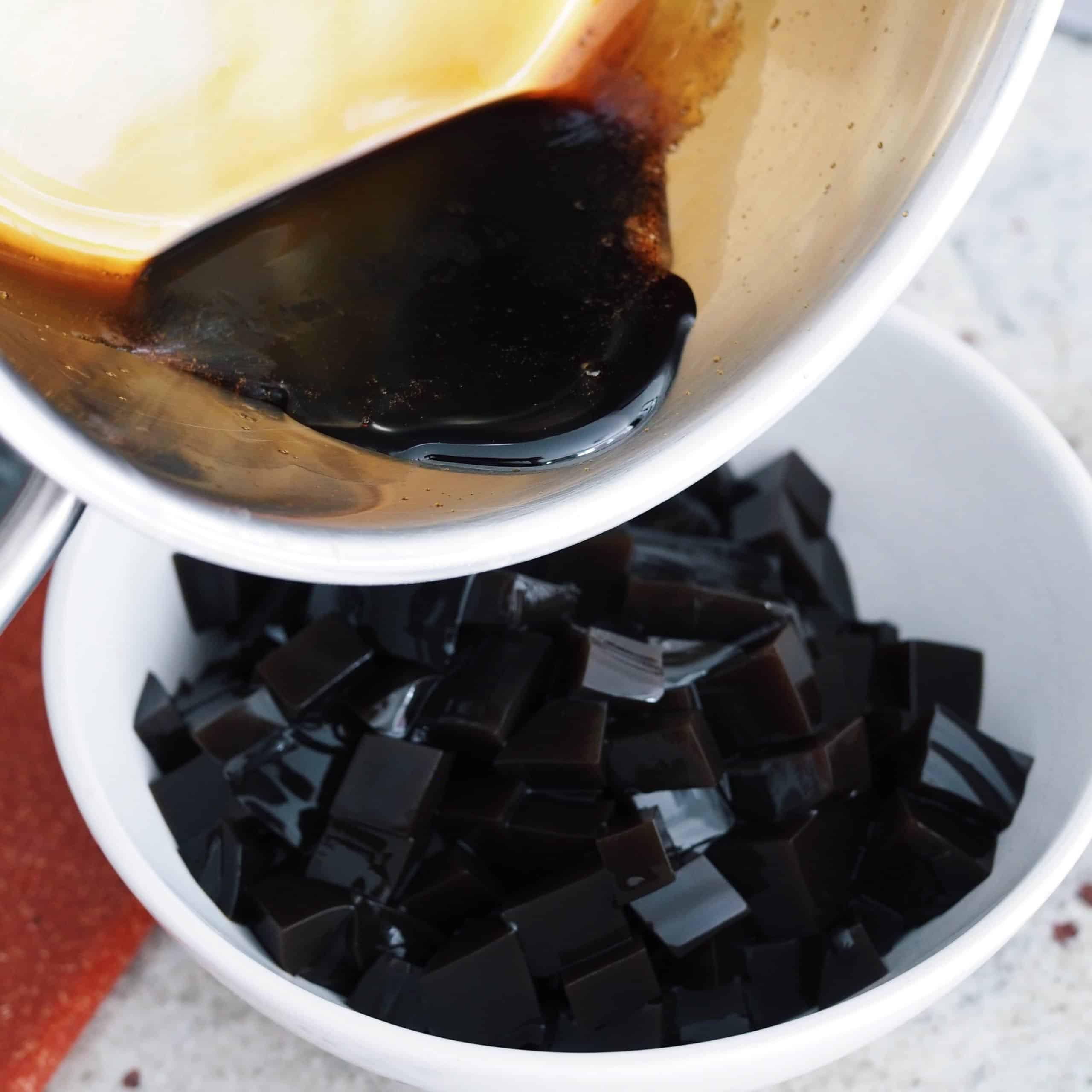 Take half of the brown sugar syrup and save the remaining half to garnish the glasses later. Divide the half portion of syrup between the two bowls of grass jelly cubes. Gently mix syrup into the grass jelly with a spatula.