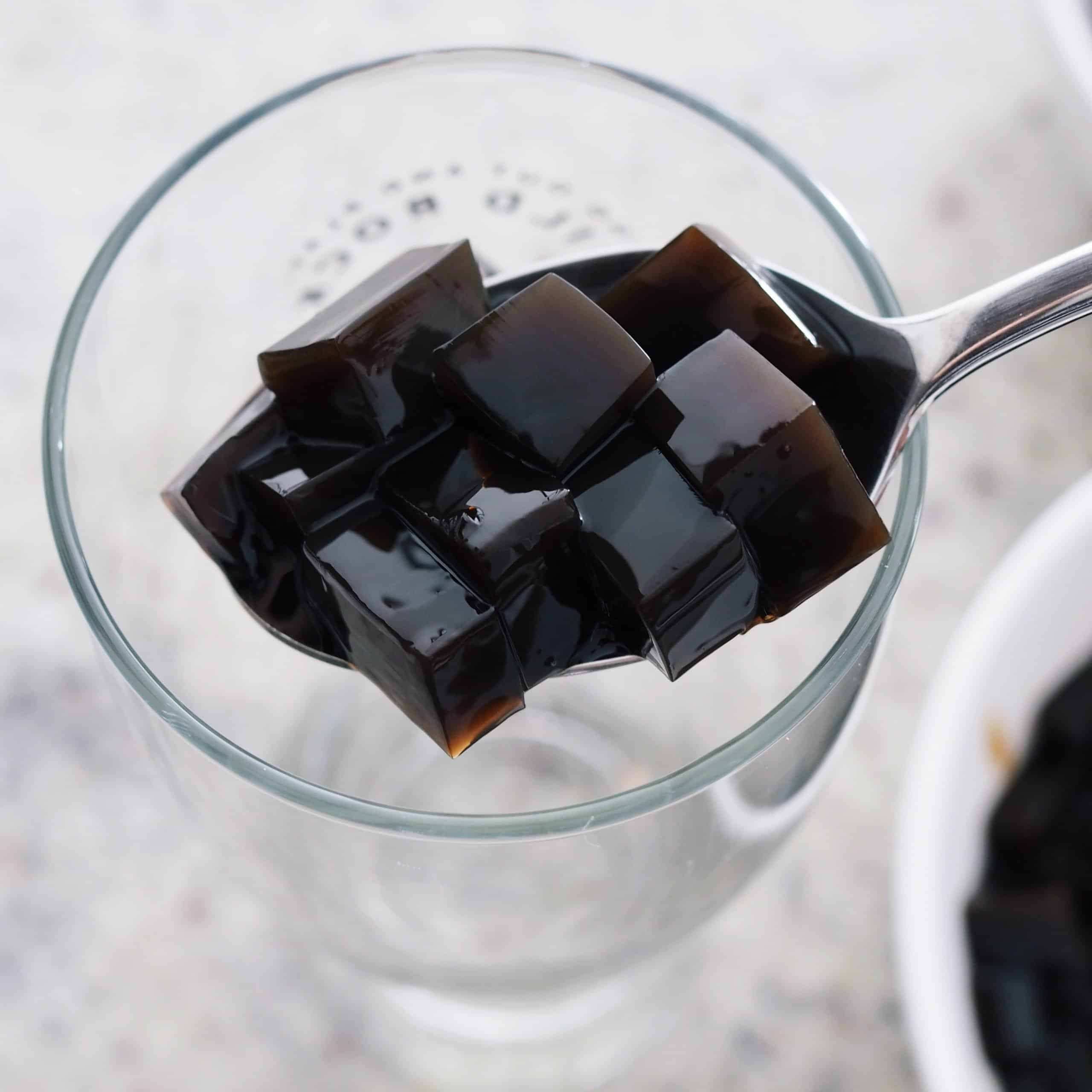 In a tall glass, spoon a variety of the grass jelly cubes into the base.