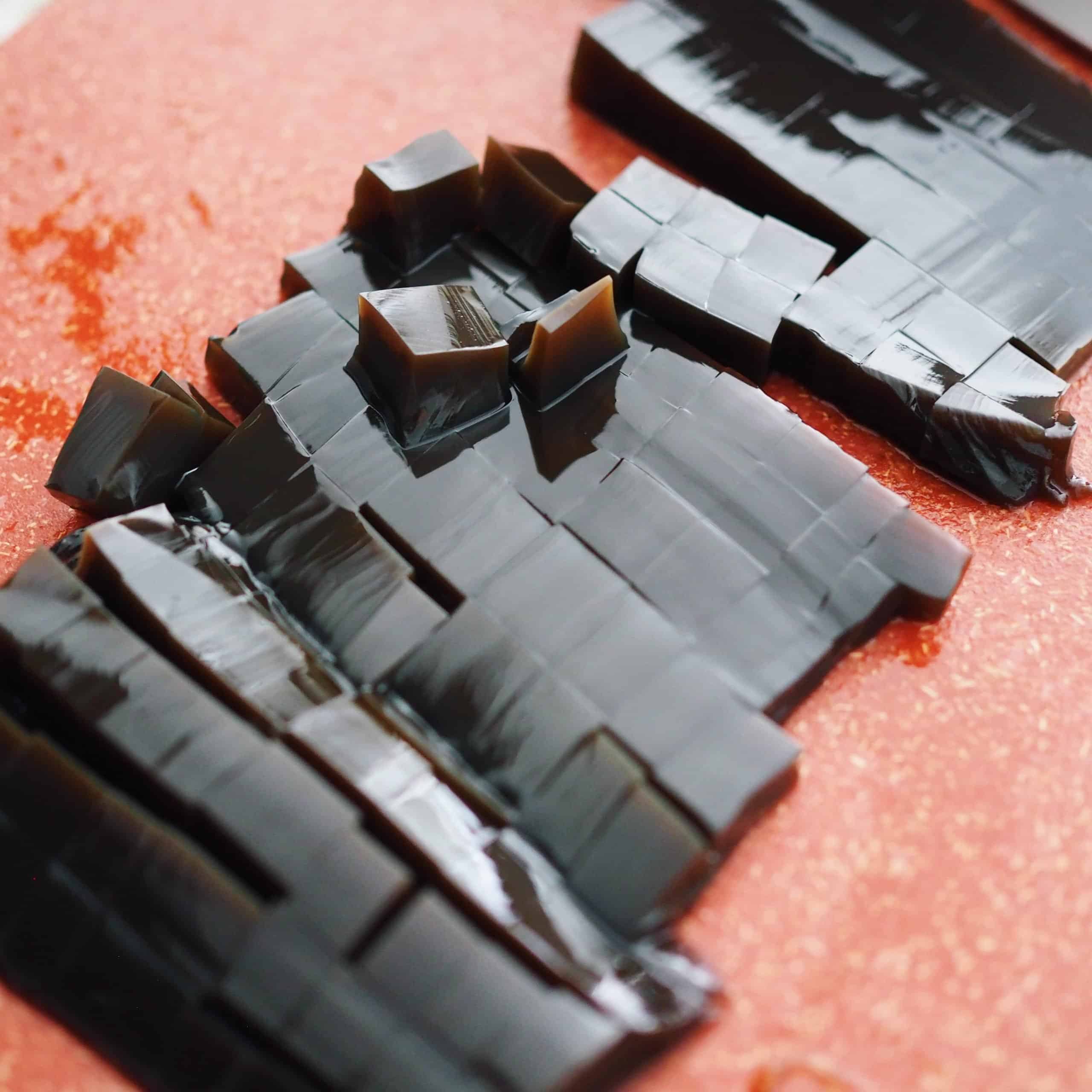 Open your canned grass jelly and pop the jelly out onto a cutting board. Warning: it's very slippery! Slice the jelly into half. Slice one half of the portion into little cubes and the other half into medium size cubes. This is optional but it gives you a variety of texture. Place the grass jelly cubes into two separate bowls.