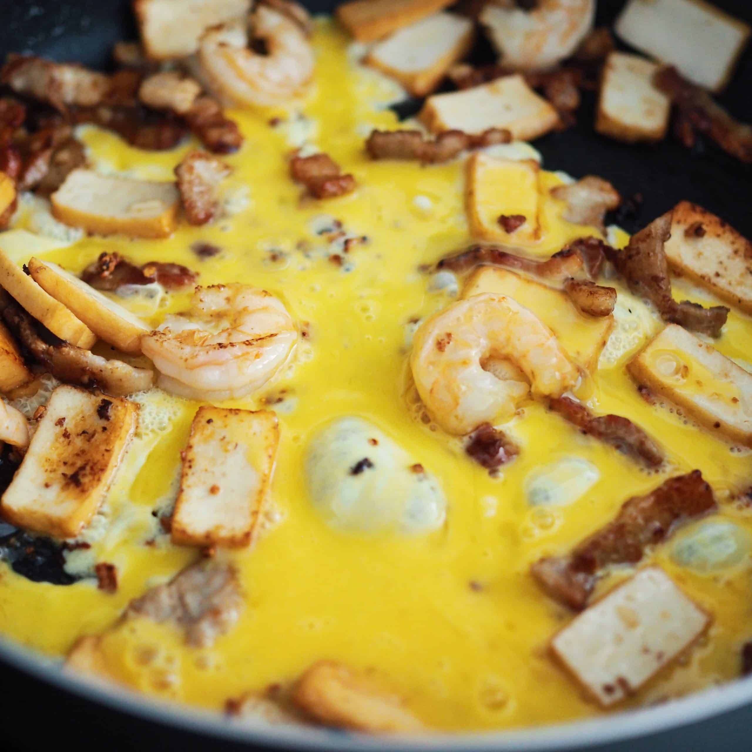 Sweep your ingredients to the side of the pan. Pour in beaten eggs to scramble them and toss with the other ingredients.