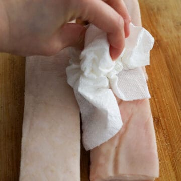 Then turn the pork belly over skin side up and wipe it with a clean paper towel to remove any dry rub or excess moisture as best as possible.