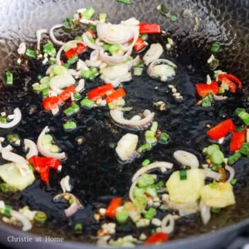 Add the remaining oil into the pan and sauté red chili, green onions, shallot, garlic, and ginger for 15 seconds, or slightly softened.
