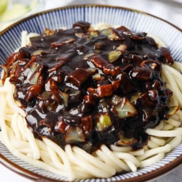 Boiling noodles until al dente, draining without rinsing, then adding sauce, topping with julienned cucumber, and mixing to serve