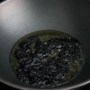 Frying black bean paste in a pan of hot oil while stirring, then transferring to a bowl and reserving a small amount of oil