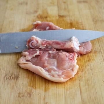 Debone the chicken thighs by carefully making small cuts around the bone with a sharp knife until it can be easily removed