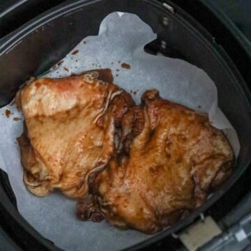 Evenly spray the air fryer basket with vegetable oil and place the chicken thighs in a single layer, skin-side up.
