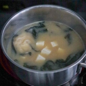 Stir in dried wakame seaweed and allow it to expand. Then gently add diced tofu. Finally serve and garnish with green onions and enjoy!