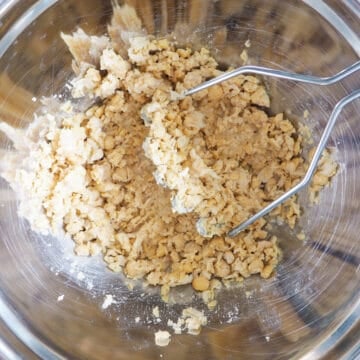 Rinse your canned chickpeas with cold water several times to remove the odor from the chickpea liquids. Strain them. In a large bowl, smash your strained chickpeas with a potato masher until mashed to the consistency that you desire. You may also pulse them in a food processor.