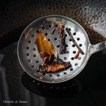 Remove the aromatics from the hot oil with a slotted spoon and discard them.