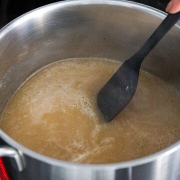 A pot of broth simmering with soy sauce, oyster sauce, and seasonings mixed in.