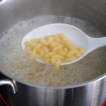 A pot of salted water at a rolling boil with macaroni cooking until tender.