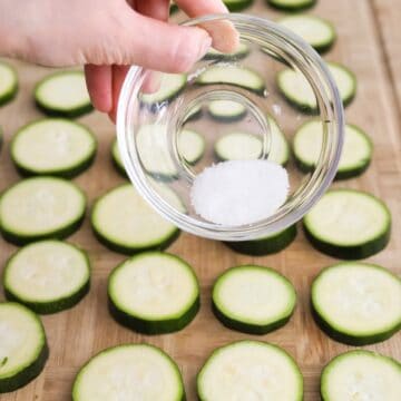 Evenly sprinkle salt on both sides of the zucchini slices. Let them sit for 10 minutes to draw out excess liquid. Then lightly dab zucchini with a clean kitchen paper towel to remove excess moisture.