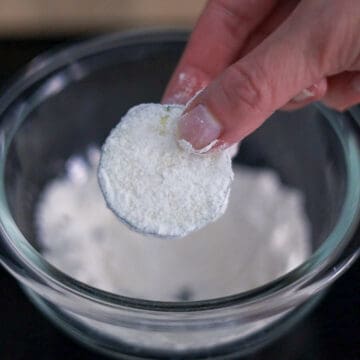 Prepare a shallow bowl of potato starch or all-purpose flour and evenly coat zucchini slices in it, ensuring no bald spots. Shake off any excess starch or flour.