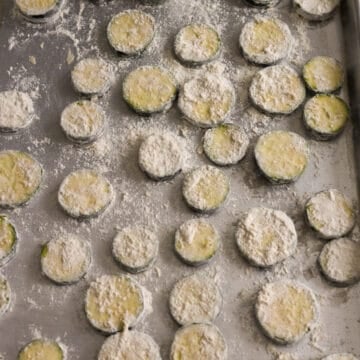 Then transfer floured zucchini in a single layer onto a large baking tray lined with parchment paper. Do not overlap them.