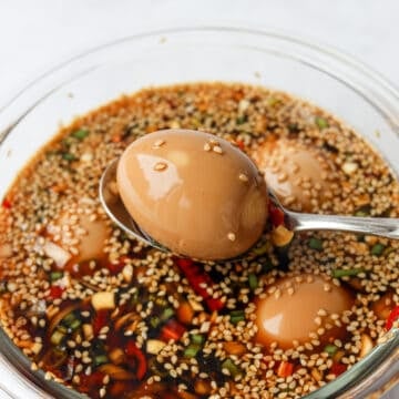 Seal the container with a lid and marinate the eggs in the fridge for at least 5 hours or overnight for best results. To enjoy, remove an egg from the marinade, slice into half and serve with steamed rice with a drizzle of the marinade on top. Leftover eggs can be stored in the marinade in the same container in the fridge.