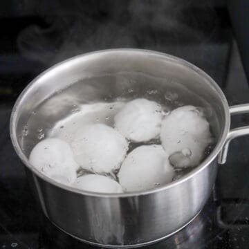 Bring a small pot of water to boil on medium-high heat and add salt and vinegar. Gently lower in room temperature eggs and reduce to medium heat for a rolling boil. Do not cover. Set a timer and soft boil for 6.5 mins or 10 minutes for hard-boiled eggs.
