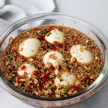 Gently submerge the eggs into marinade and place a square piece of clean paper towel or plastic wrap on top of the eggs to push them deeper into the marinade for a more even brown color.