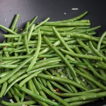 Toss in green beans. Once tossed, add water to help cook them faster.