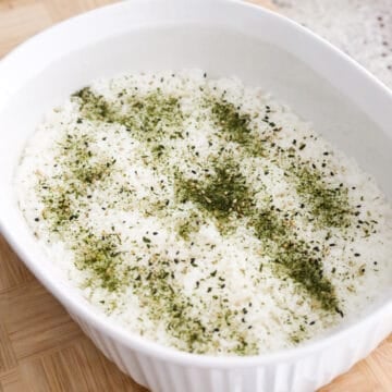 Then transfer seasoned rice to a lightly greased 9 x 11-inch baking dish. Firmly flatten and pack the rice down into the dish with a wet rice paddle. Sprinkle 1 teaspoon of furikake on top of the rice.