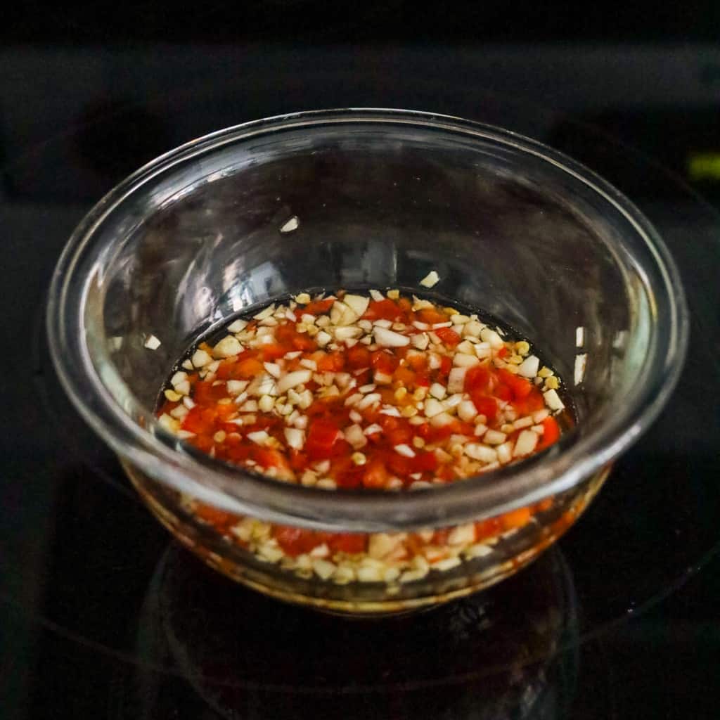 In a small bowl, combine water, sugar and fish sauce. Mix until sugar has dissolved. Mix in minced red chilies and garlic. Serve with egg rolls and enjoy!