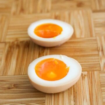 A marinated egg sliced in half on a wooden cutting board to reveal a jammy yolk.