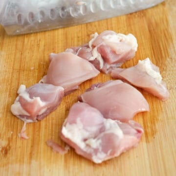 Raw chicken thighs cut into 1.5-inch cubes in a large mixing bowl, ready for preparation.