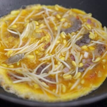 Heat vegetable oil in a medium-sized pan (about 7-8 inches wide) or a wok on medium-high heat. Pour in omelette mixture into the hot pan and evenly spread out shrimp and other ingredients with chopsticks.