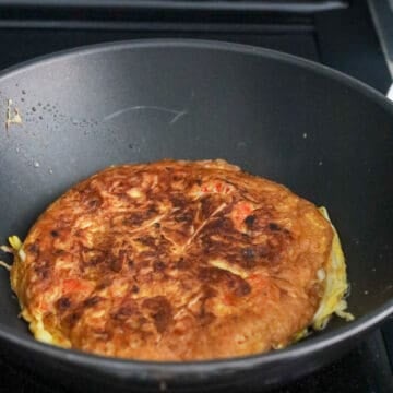 Fry omelet on the first side for 3 minutes until the bottom is golden brown and crispy. Flip over with a large spatula and fry on the other side for 2 mins, until golden and crispy. Remove and transfer omelet to serving plate.Â