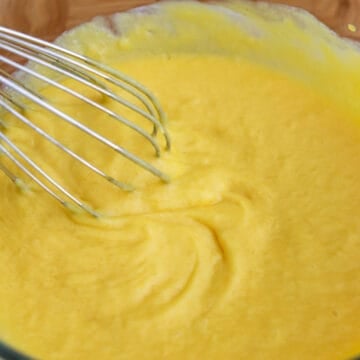 Sugar, coconut milk, and mango purée being stirred into the bloomed gelatin until smooth and fully combined.