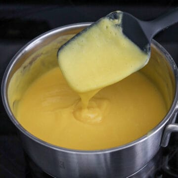 Mixture being gently heated in a pot over low heat while whisking until the gelatin fully dissolves without boiling.
