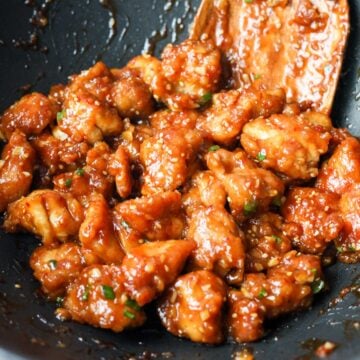 Once sauce has thickened, toss in cooked chicken. Remove off heat. Garnish with green onions and sesame seeds and enjoy!