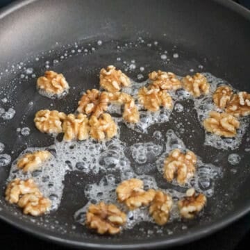 Once the syrup thickens and can coat the back of your spatula, quickly add walnuts. Mix to coat evenly.