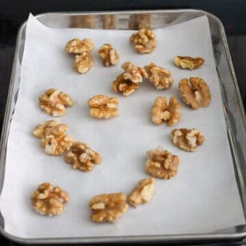 Once coated and a crust has formed around each walnut, immediately remove pan off the heat and remove candied walnuts one by one with tongs and transfer to parchment paper spreading them apart. Set aside.