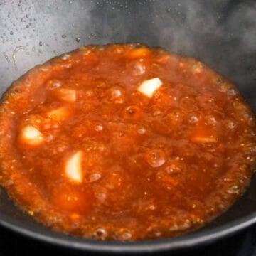 Sautéed onions cooking in a pan, followed by sauce being added and simmering until thickened.