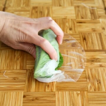 From the end closest to you, roll the rice paper away from you tucking the lettuce and noodles in. Then roll and tuck in the shrimp and mint leaves. Finally tuck in the sides of the rice paper and finish rolling.