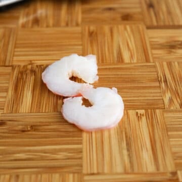Allow the shrimp to cool before peeling off the shells. Carefully slice each shrimp in half with a sharp knife. If needed, devein shrimp at this point by removing the black vein.