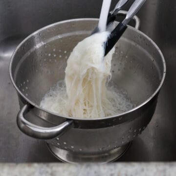 Bring a large pot of water on high heat, bring to a boil. Cook rice noodles for 2-3 minutes or until Al dente. Strain and rinse with off cold running water. Shake out any excess water. Transfer to a large bowl.