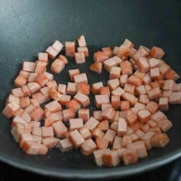 Dice spam into small cubes, about 1 cm x 1 cm. Heat vegetable oil in a large pan on medium-high heat. Fry diced spam for 2-3 minutes or until lightly golden brown on the edges. Remove and set aside.Â