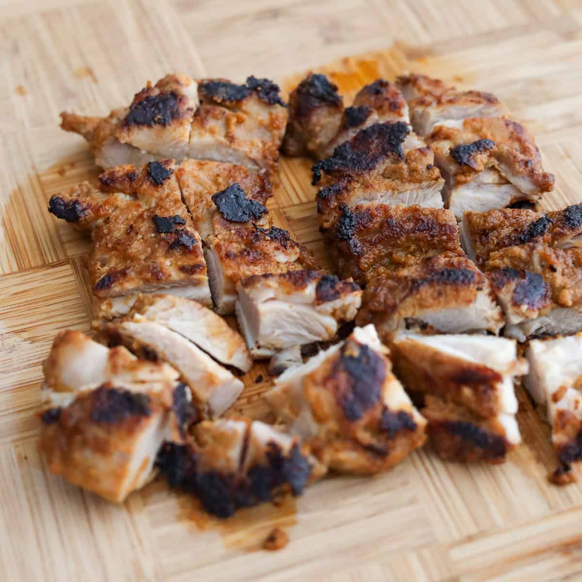 Cooked chicken resting on a plate before being diced into bite-sized pieces to retain juices.