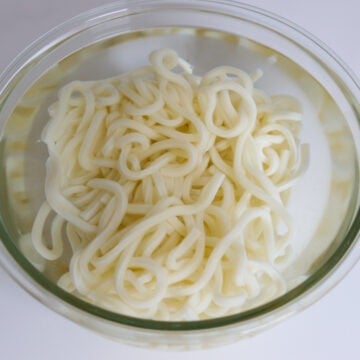 In a large bowl, soak frozen udon noodles in hot boiling water just until loosened, about 30-60 seconds. Strain immediately in a colander and set aside.