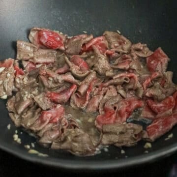 Next add in thawed thinly sliced beef and stir fry until 60% cooked. Remove from the pan and set aside.