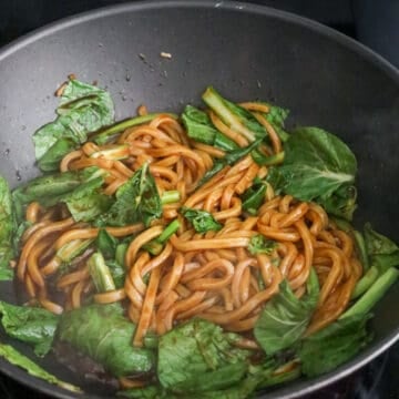 Increase to medium-high heat, add udon noodles with noodle sauce. Mix well and cook until sauce has slightly thickened and isn’t so runny. Toss in greens and cook until they’re softened.Â