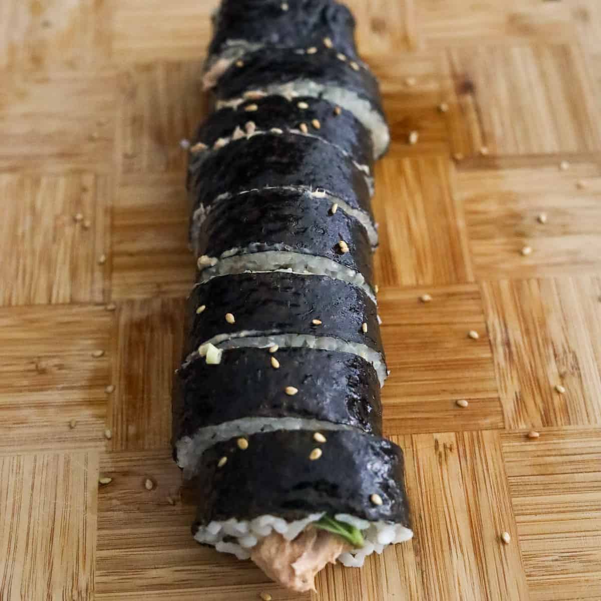 Next carefully brush or rub some sesame oil onto the sides of a sharp knife. Firmly hold the kimbap roll with your dominant hand (but don't squeeze) and slice it with the knife into 1-inch-thick pieces. Then garnish with sesame seeds. Enjoy!