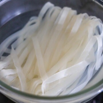 In a large bowl, soak dried rice noodles in hot boiling water for 4 minutes until limp and firm. Strain immediately. Rinse with cold water until cool to touch. Gently separate any noodles that are stuck together with your hands and set aside.