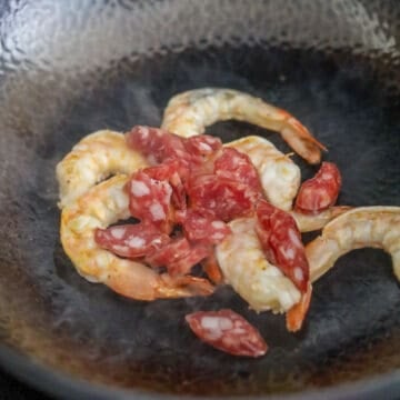 Heat 1 tablespoon or 15 ml of vegetable oil in a large pan or wok on medium-high heat. Fry shrimp until pink and slightly curled. Then fry the sliced sausage for 30 seconds. Remove and set aside.