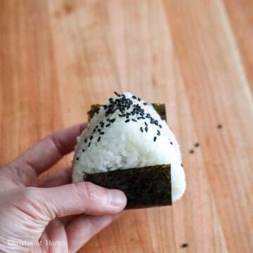 Wrap a sheet nori from the base of the triangle around the sides and repeat this process until you have 4 rice balls in total. Garnish each piece with sesame seeds. Enjoy immediately!
