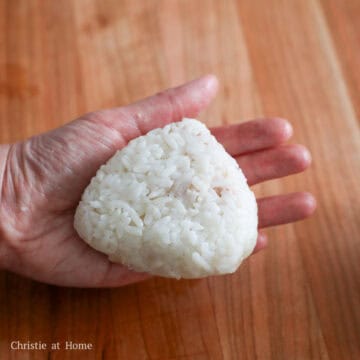 Fold the rice over the filling and as you fold, push the filling into the center. Firmly pack it into a ball, flatten it so it's 1.5-inch thick and shape it into a triangle, wetting your hands as needed.
