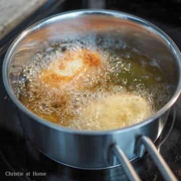 Golden croquettes being deep-fried in hot oil in a pan until crispy and browned.